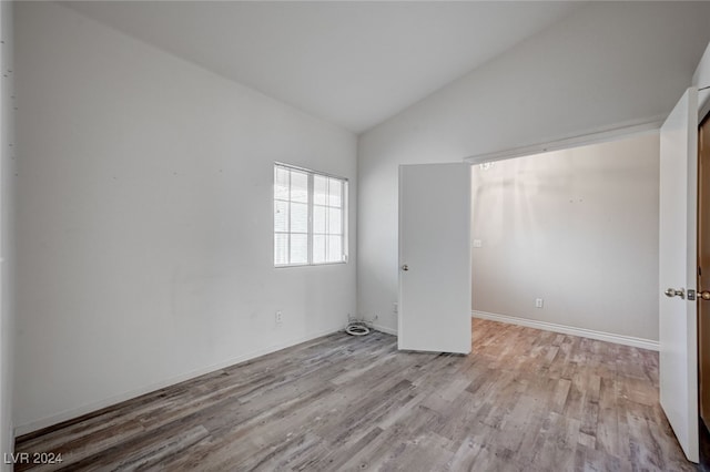 spare room featuring vaulted ceiling and light hardwood / wood-style floors