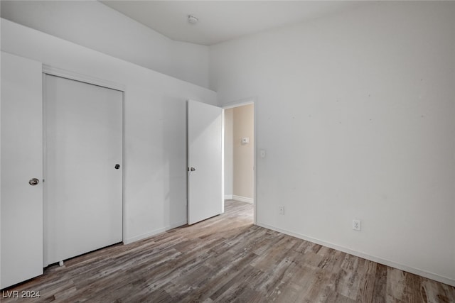 unfurnished bedroom with a towering ceiling, a closet, and light hardwood / wood-style floors