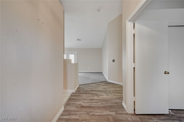 hall featuring lofted ceiling and light hardwood / wood-style flooring