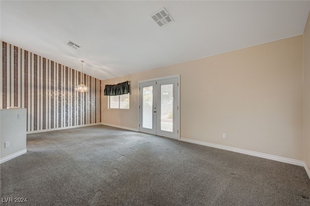 empty room with a notable chandelier, french doors, and carpet