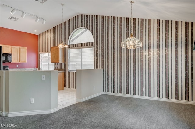 kitchen with hanging light fixtures, light carpet, track lighting, light brown cabinetry, and vaulted ceiling