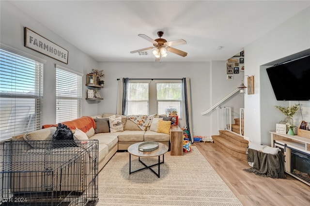 living area featuring a healthy amount of sunlight, ceiling fan, stairs, and wood finished floors