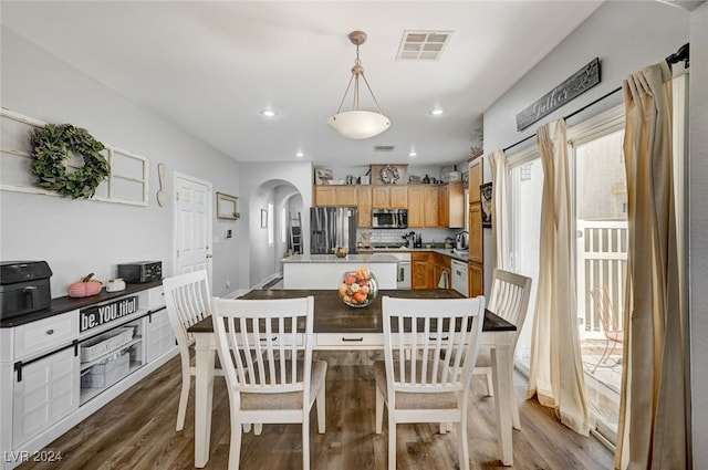 dining area with dark wood-style floors, visible vents, arched walkways, and recessed lighting