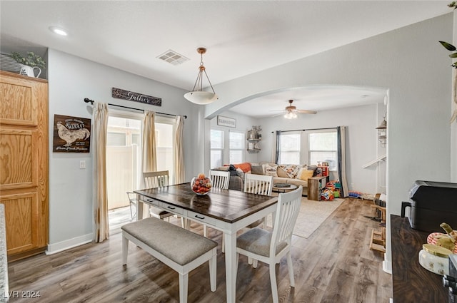 dining room featuring baseboards, visible vents, arched walkways, ceiling fan, and wood finished floors