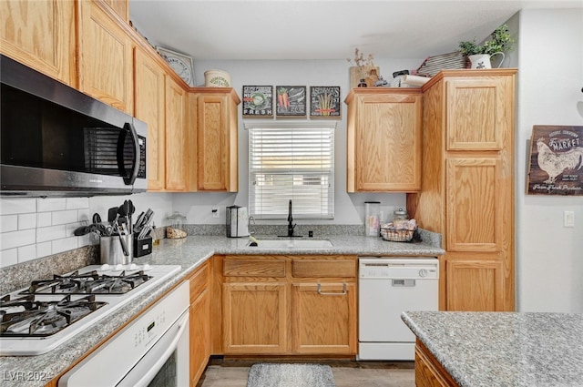 kitchen featuring white appliances, light countertops, a sink, and decorative backsplash