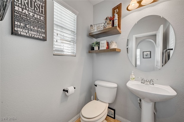 bathroom with toilet, baseboards, and a sink