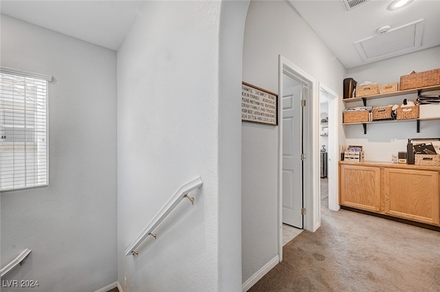 corridor featuring attic access and light colored carpet