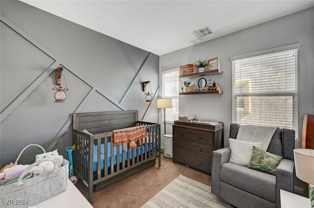 bedroom featuring light carpet, a nursery area, and visible vents