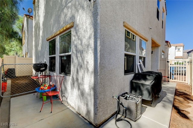 view of side of home with fence, a patio, and stucco siding