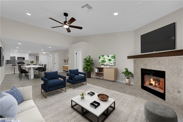 living room featuring ceiling fan, lofted ceiling, and a tiled fireplace