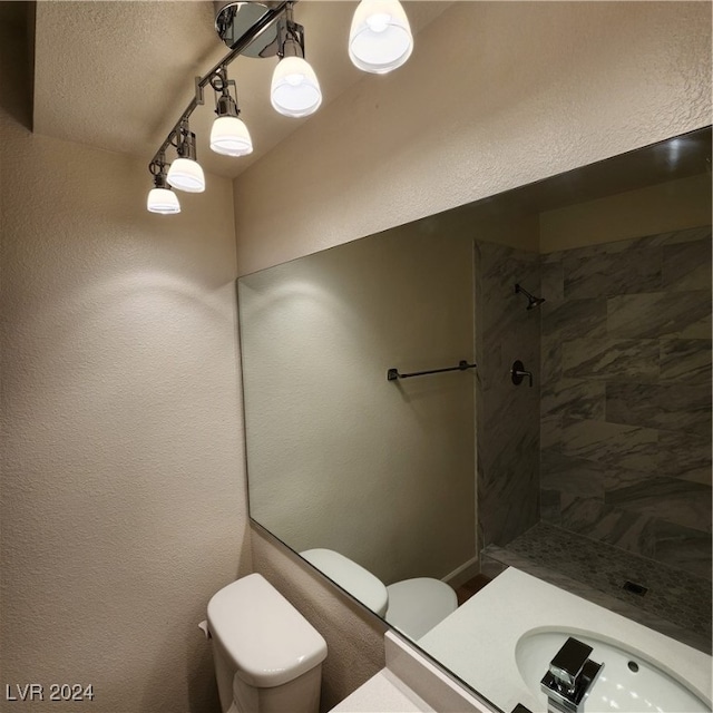 bathroom featuring a tile shower, vanity, and toilet