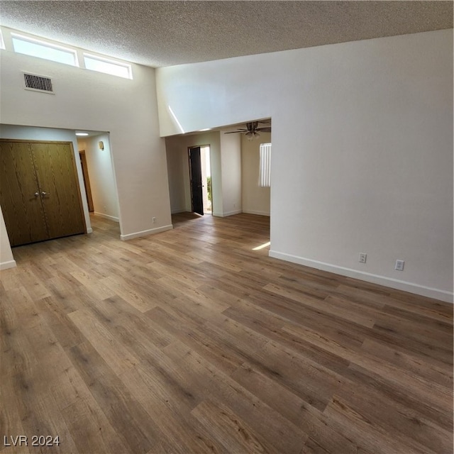 spare room with ceiling fan, a textured ceiling, hardwood / wood-style floors, and a high ceiling