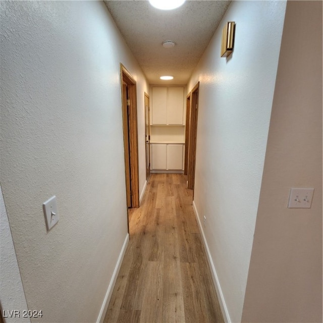 corridor featuring light hardwood / wood-style floors and a textured ceiling