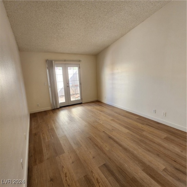 unfurnished room featuring french doors, light wood-type flooring, and a textured ceiling