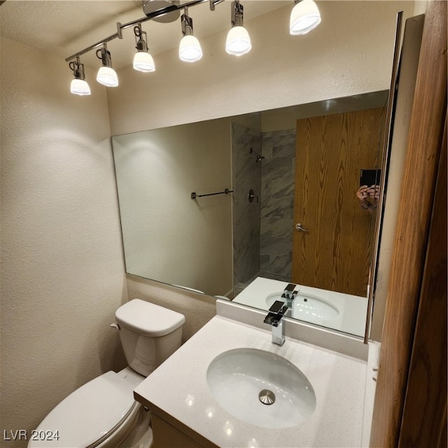 bathroom featuring a textured ceiling, walk in shower, vanity, and toilet