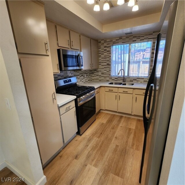 kitchen with light hardwood / wood-style floors, stainless steel appliances, sink, and decorative backsplash