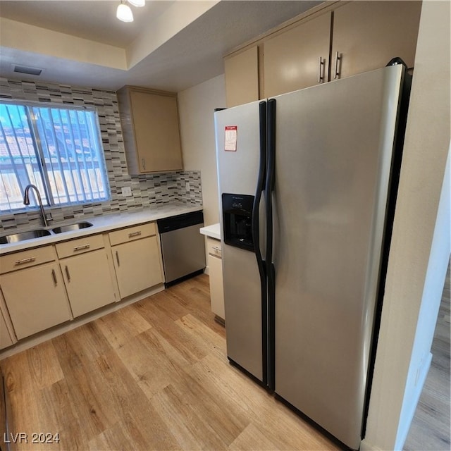 kitchen featuring sink, tasteful backsplash, light hardwood / wood-style flooring, a tray ceiling, and stainless steel appliances