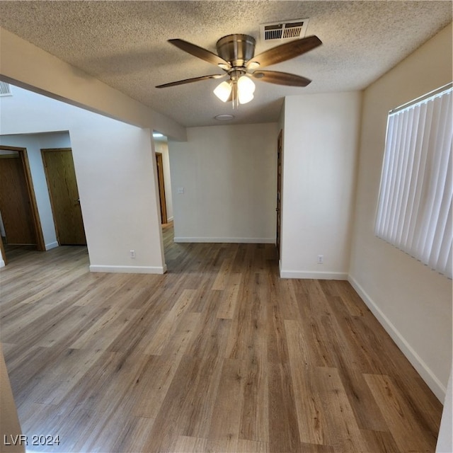 empty room with light hardwood / wood-style floors, a textured ceiling, and ceiling fan