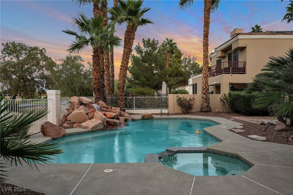 pool at dusk with an in ground hot tub