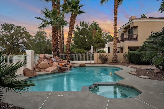 pool at dusk with an in ground hot tub