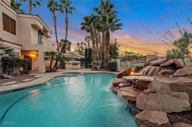 pool at dusk with an in ground hot tub, a patio, and pool water feature