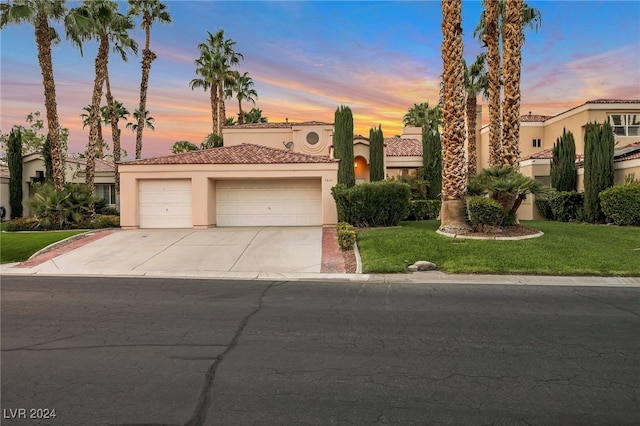 mediterranean / spanish-style home with a garage and a yard