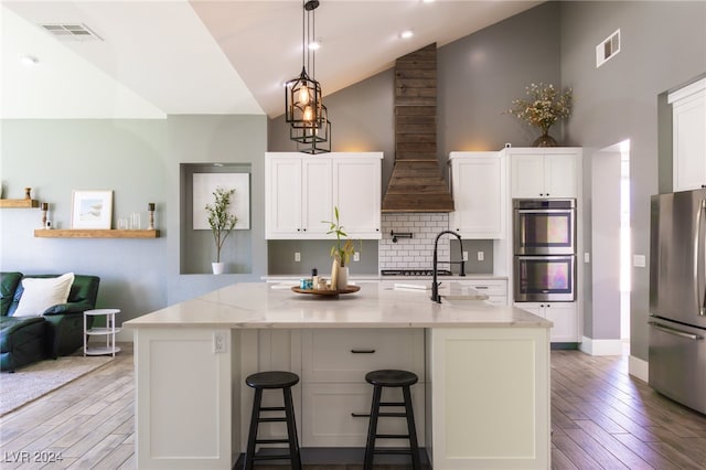 kitchen featuring light stone counters, white cabinets, stainless steel appliances, and a spacious island