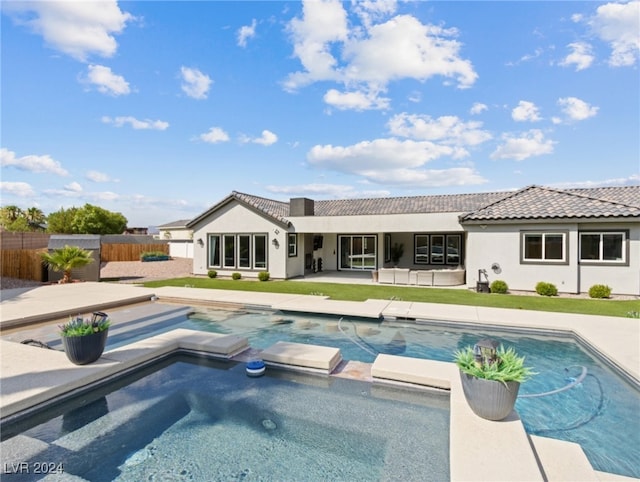 rear view of house featuring a swimming pool with hot tub and a patio area