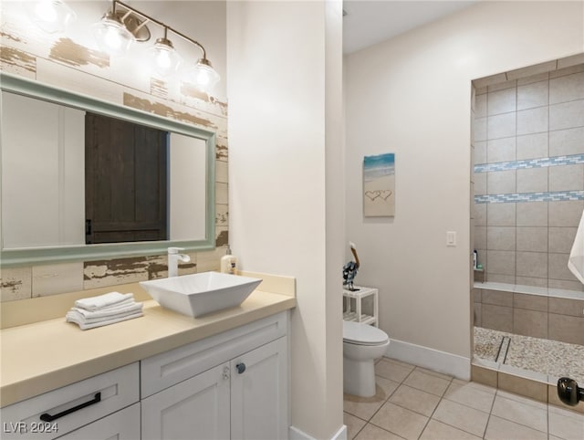 bathroom featuring a tile shower, vanity, toilet, and tile patterned floors