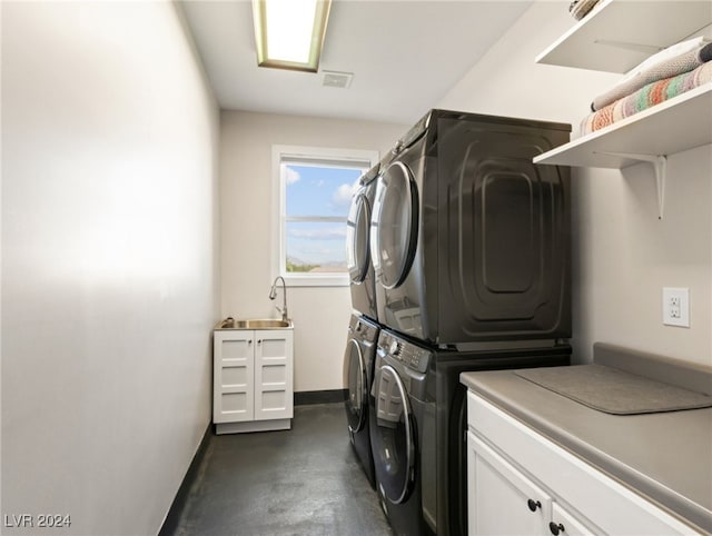 clothes washing area featuring stacked washer and dryer, cabinets, and sink