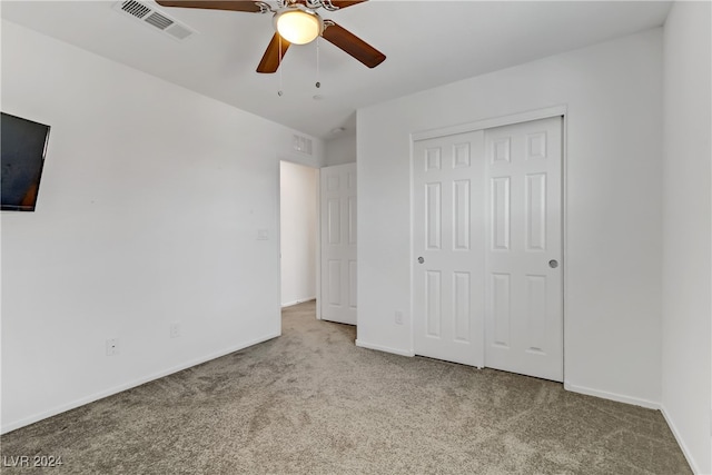 unfurnished bedroom with ceiling fan, light carpet, and a closet