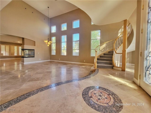 1337 Via Savona Dr, Henderson, NV 89052 - unfurnished living room featuring inlaid floor details, baseboards, a high ceiling, stairway, and a chandelier