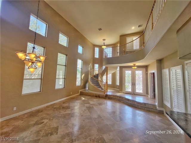 entrance foyer featuring a towering ceiling, french doors, and a notable chandelier