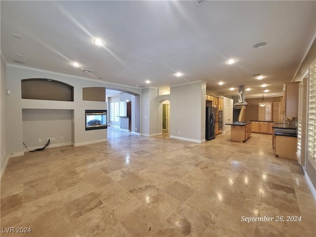 1337 Via Savona Dr, Henderson, NV 89052 - unfurnished living room featuring arched walkways, a glass covered fireplace, crown molding, baseboards, and recessed lighting