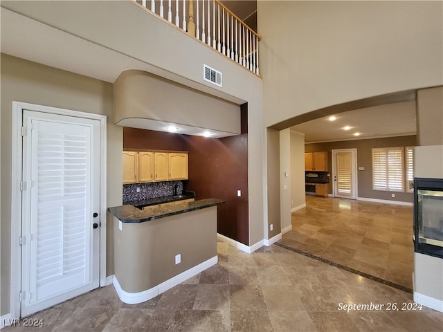 kitchen featuring kitchen peninsula, dark stone countertops, and tasteful backsplash