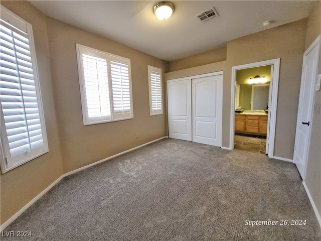 unfurnished bedroom featuring light colored carpet, a closet, and ensuite bathroom