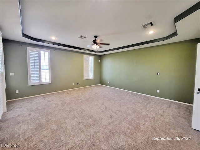 spare room featuring ceiling fan, a tray ceiling, and carpet