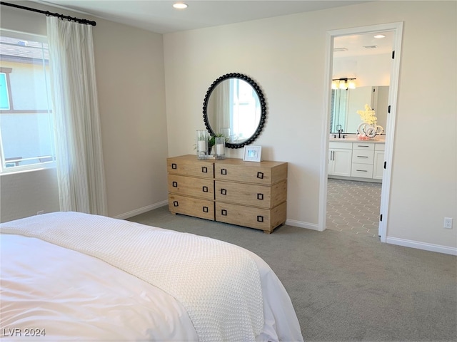 bedroom with connected bathroom, sink, and light colored carpet