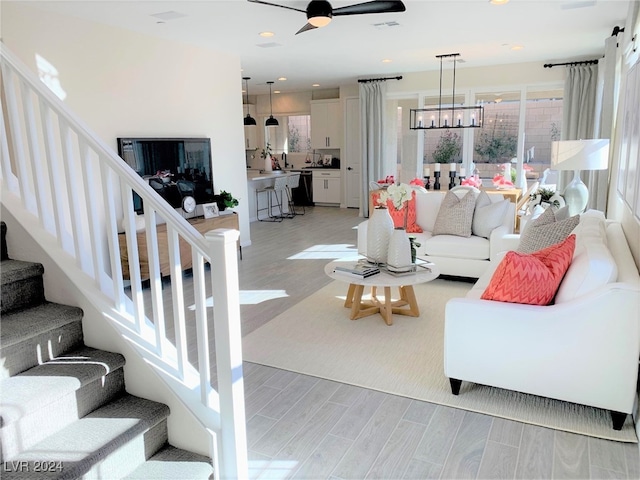 living room featuring light hardwood / wood-style flooring and ceiling fan with notable chandelier