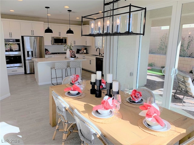 dining space featuring light hardwood / wood-style floors, a notable chandelier, and sink