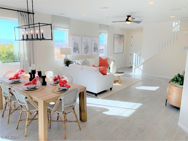 dining space featuring light hardwood / wood-style flooring and ceiling fan with notable chandelier