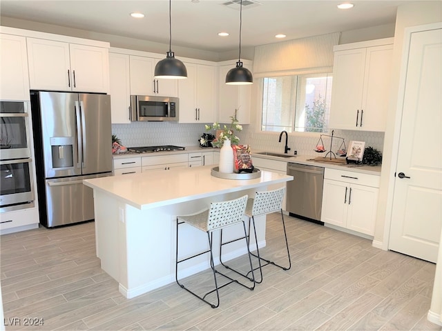 kitchen featuring light hardwood / wood-style flooring, sink, a center island, white cabinetry, and appliances with stainless steel finishes