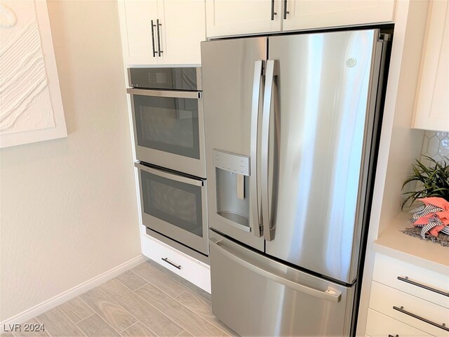 kitchen with appliances with stainless steel finishes, white cabinetry, and light hardwood / wood-style floors