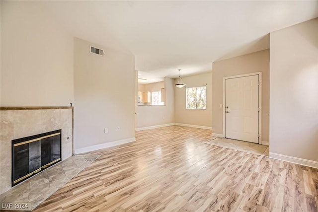 unfurnished living room with a tile fireplace and light hardwood / wood-style flooring