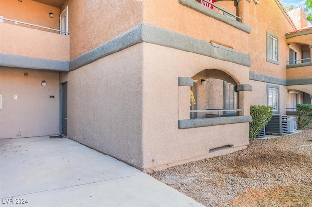 view of property exterior featuring a patio area, cooling unit, and a balcony