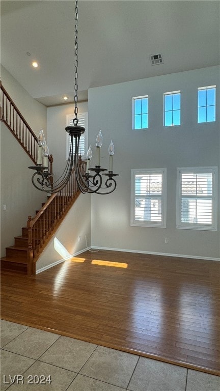 interior space with a towering ceiling, a notable chandelier, and light hardwood / wood-style flooring