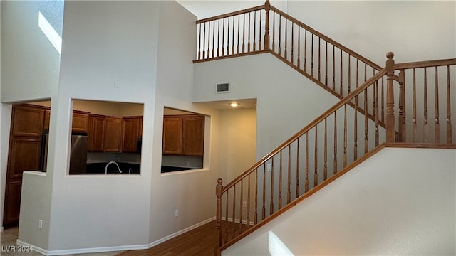 stairs featuring wood-type flooring and a high ceiling