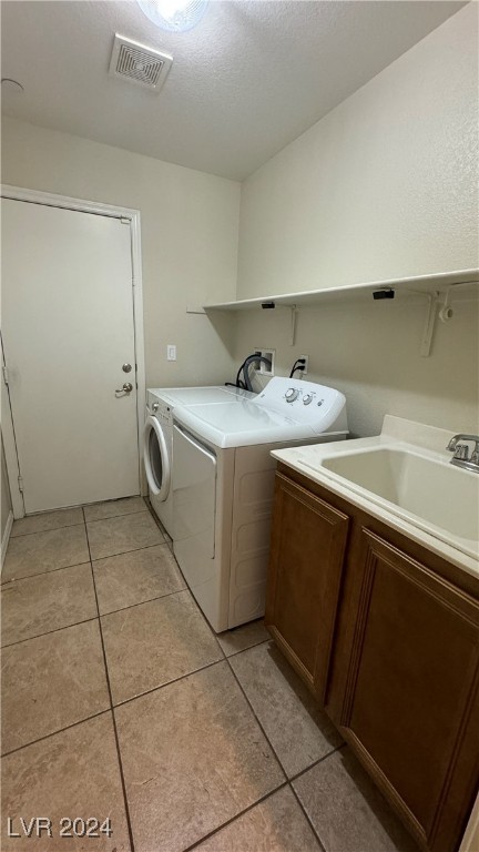 laundry area with cabinets, separate washer and dryer, light tile patterned floors, and a textured ceiling