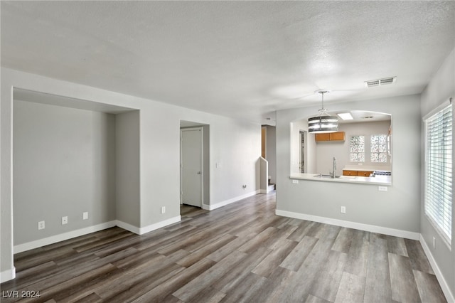 unfurnished living room featuring sink, a textured ceiling, and hardwood / wood-style flooring