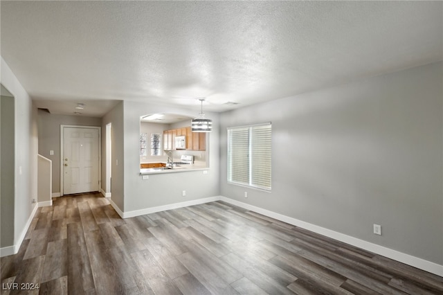 unfurnished living room featuring hardwood / wood-style floors and a textured ceiling